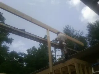 Carpenter setting a ridge beam over a new addition frame — Ice Dam Removal by Roofing Brothers in Drake