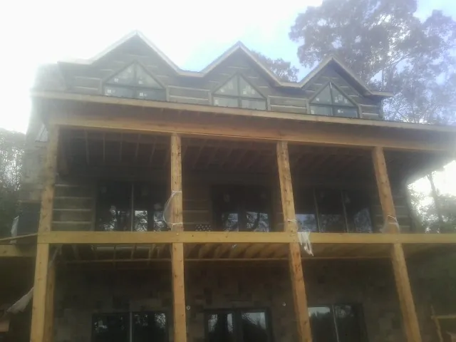 Dormers and porch framing on a large log home under construction — Roof Coating work by our crew in Drake